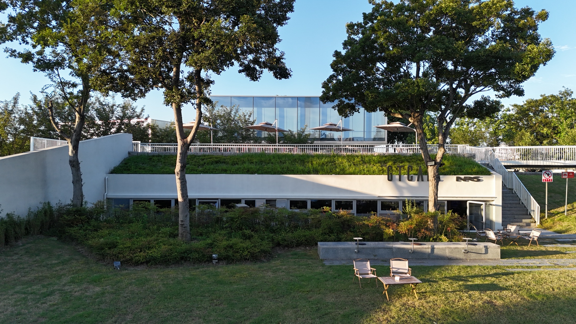 GTCAFE 咖啡馆建筑、露台和前方草坪的傍晚实景