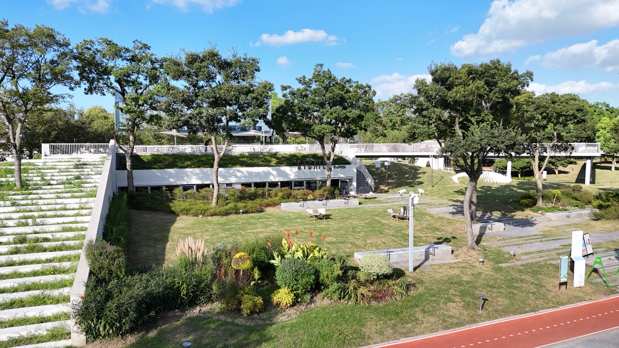晴天实拍的 GTCAFE 建筑、露台、草坪与户外步道全景